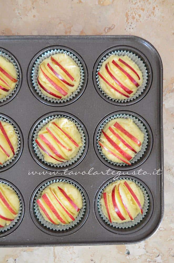 Adagiare impasto nei pirottini e fettine di mela nei muffins - Ricetta Muffins ricotta e mele