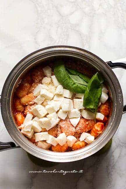 Mantecare in pentola gli gnocchi di patate con mozzarella, basilico e parmigiano - Ricetta gnocchi alla sorrentina