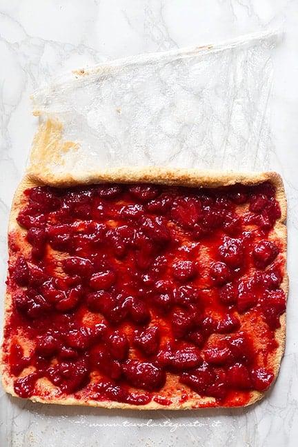 Spalmare uno strato di fragole sulla pasta biscotto - Ricetta Rotolo alle fragole