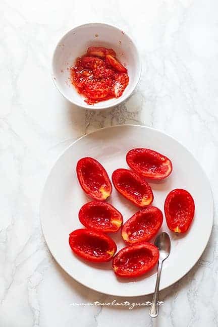 Pulire i pomodori , tagliarli a metà e svuotarli - Ricetta Caprese finger food