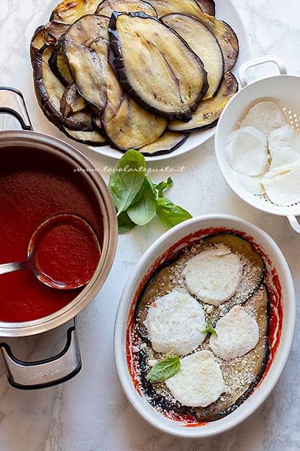Assemblare a strati la parmigiana di melanzane - Ricetta Melanzane alla parmigiana