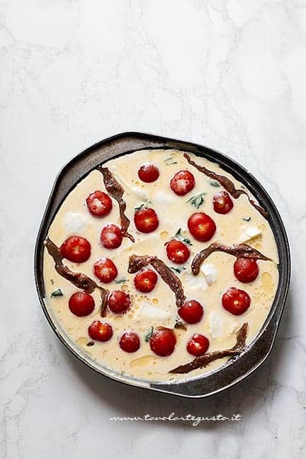 Riempire il Clafoutis salato con pomodorini, mozzarella e acciughe